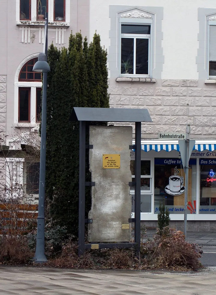 A section of the Berlin Wall set in a small memorial beside a station forecourt.