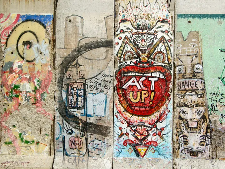 Painted sections of the Berlin Wall standing in a row on an elevated urban park.