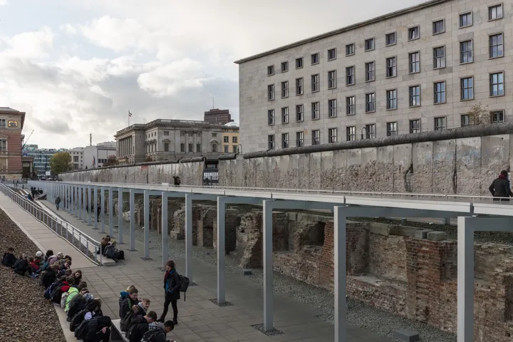 A weathered section of the Berlin Wall with holes chipped through it exposing reinforcing bars.