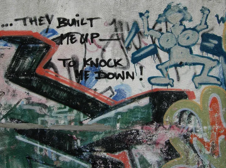 A graffiti-covered concrete wall running through a park.