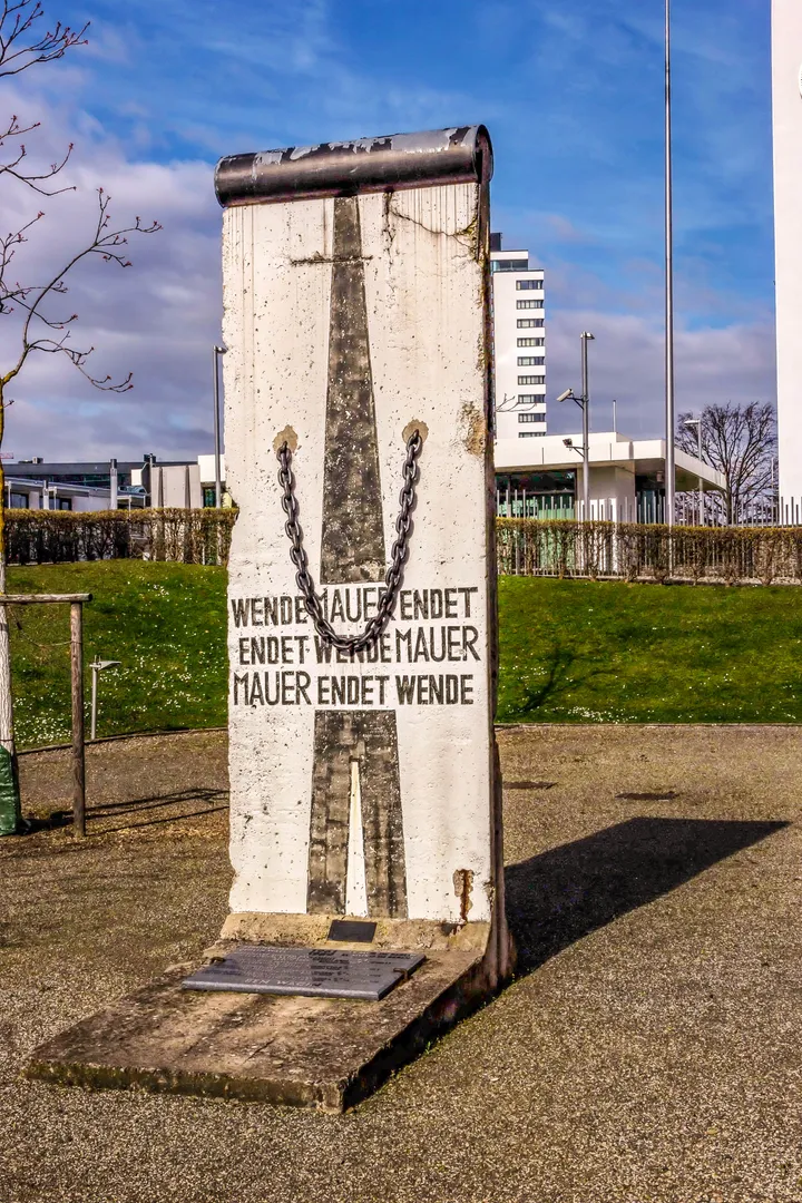 A Berlin Wall memorial standing outside a large modern office building.