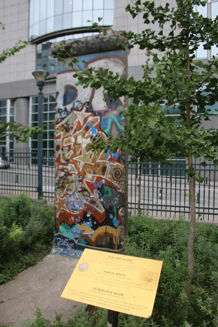A graffitied Berlin Wall segment standing among trees in a city park.