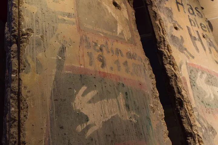Two painted Berlin Wall sections displayed indoors in a museum gallery.