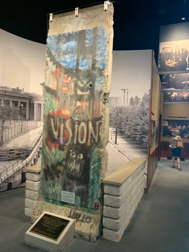A graffitied Berlin Wall segment displayed indoors in a museum gallery.