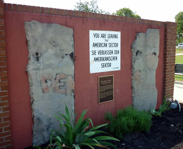 Two Berlin Wall sections mounted outdoors with an interpretive sign.