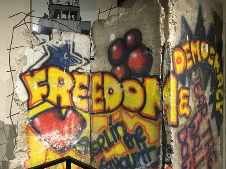 A painted Berlin Wall section displayed indoors in a museum gallery.