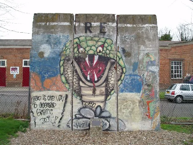 Three painted Berlin Wall segments displayed indoors in a museum gallery.