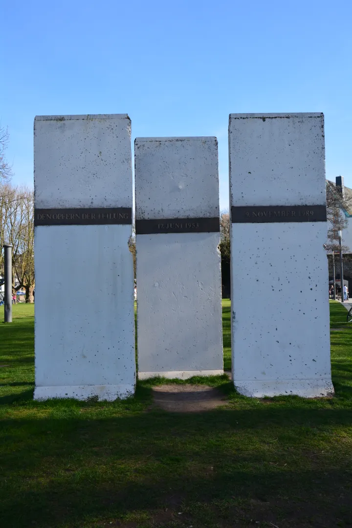 Three Berlin Wall segments standing on a riverside promenade as a memorial.