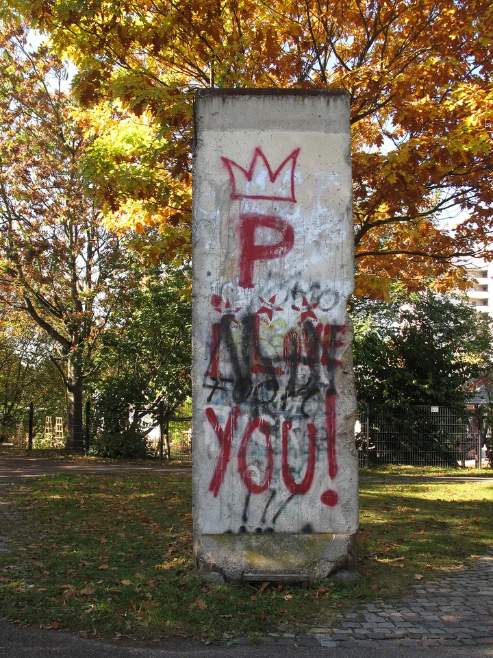 A sculptural peace memorial in a park incorporating a section of concrete wall.