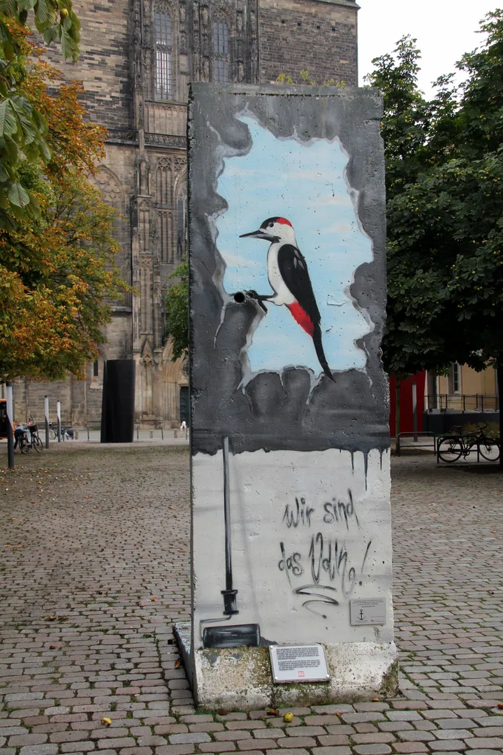 A tall painted Berlin Wall segment standing outdoors.