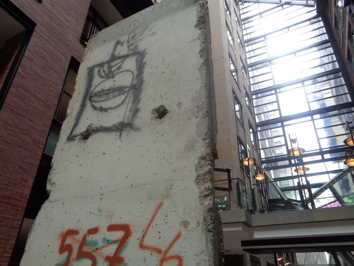 A painted Berlin Wall segment standing in a glass-roofed indoor atrium.