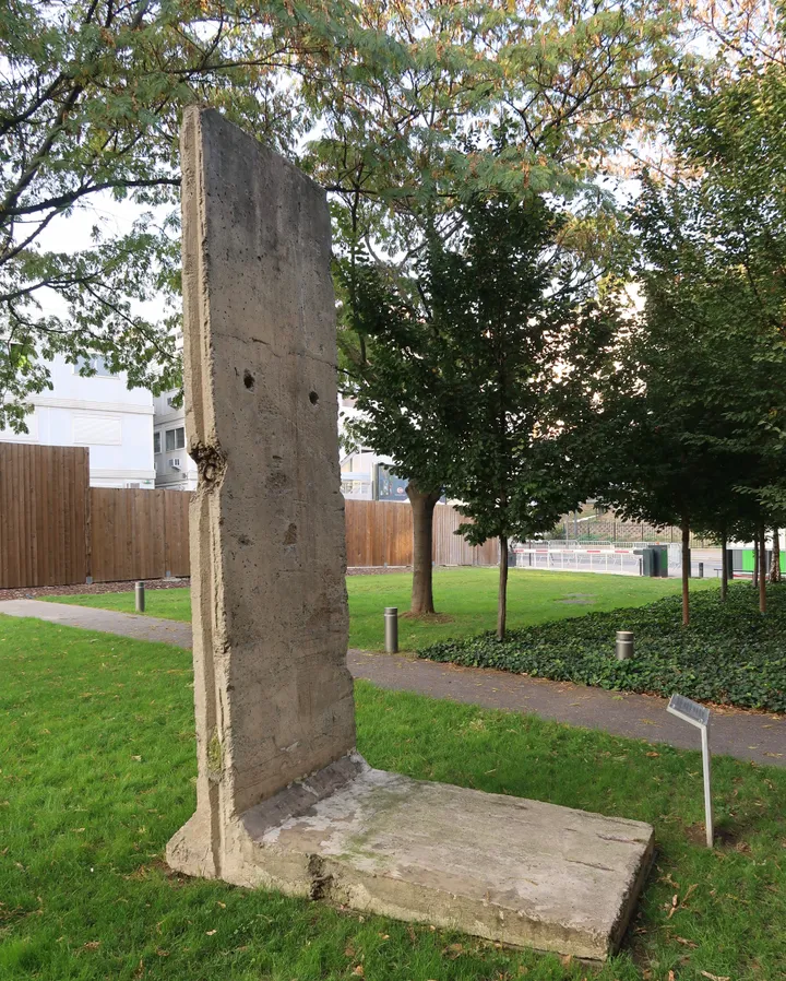 A painted Berlin Wall segment standing on grass beside a path.
