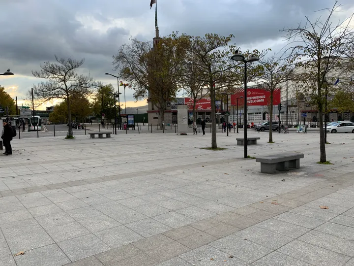 A painted Berlin Wall segment standing on a paved traffic island in a city street.