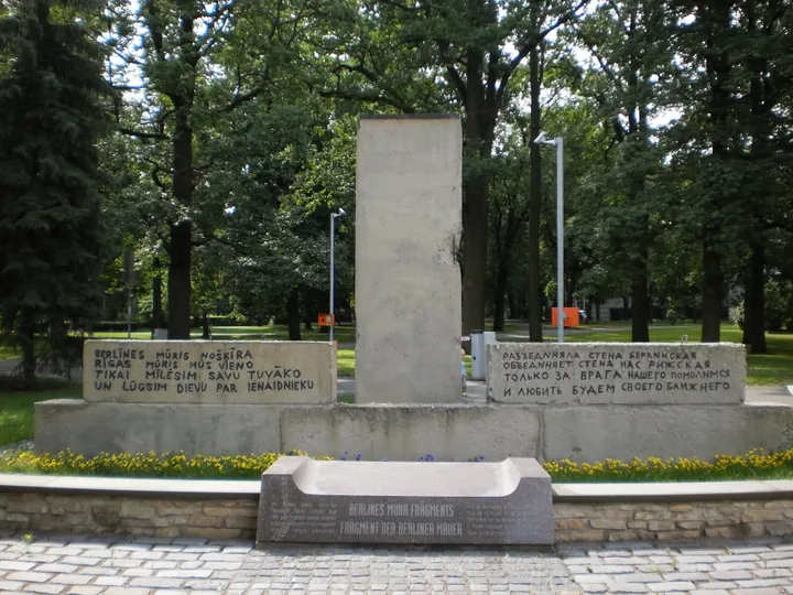 A fragment of the Berlin Wall set into a stone monument in a park.