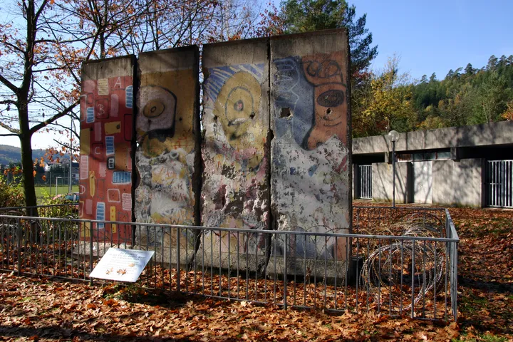 Berlin Wall segments standing on a paved area beside a school building.