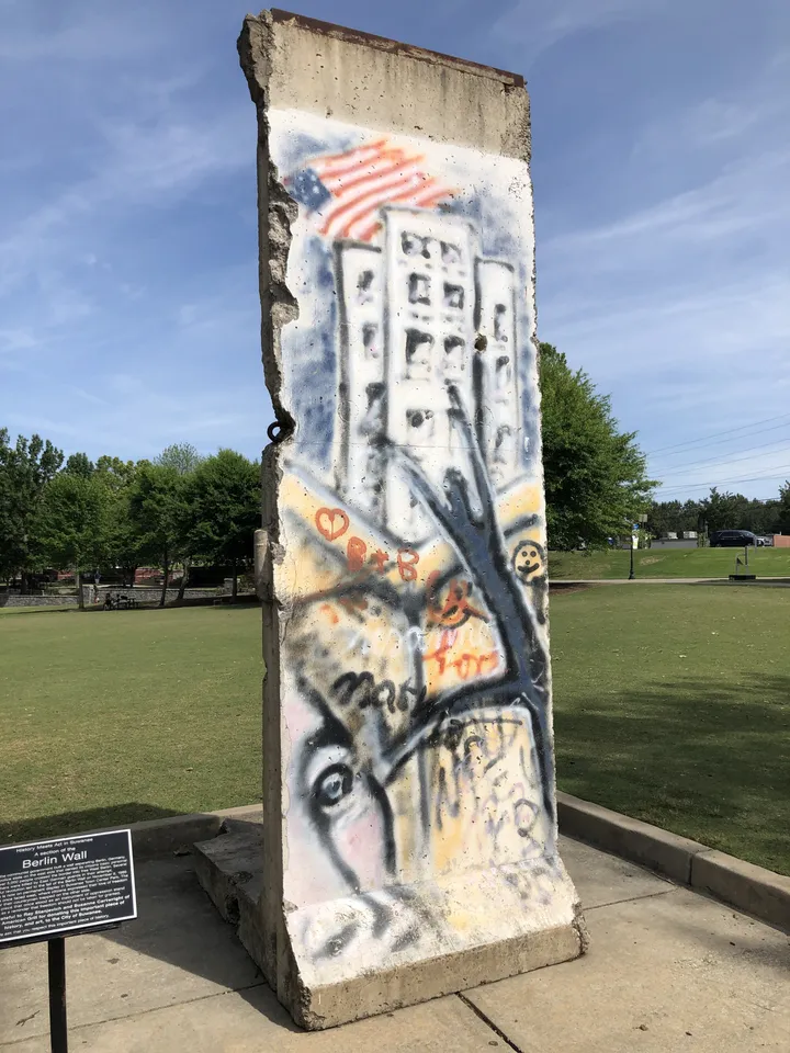 A painted Berlin Wall segment standing on grass in a public park.